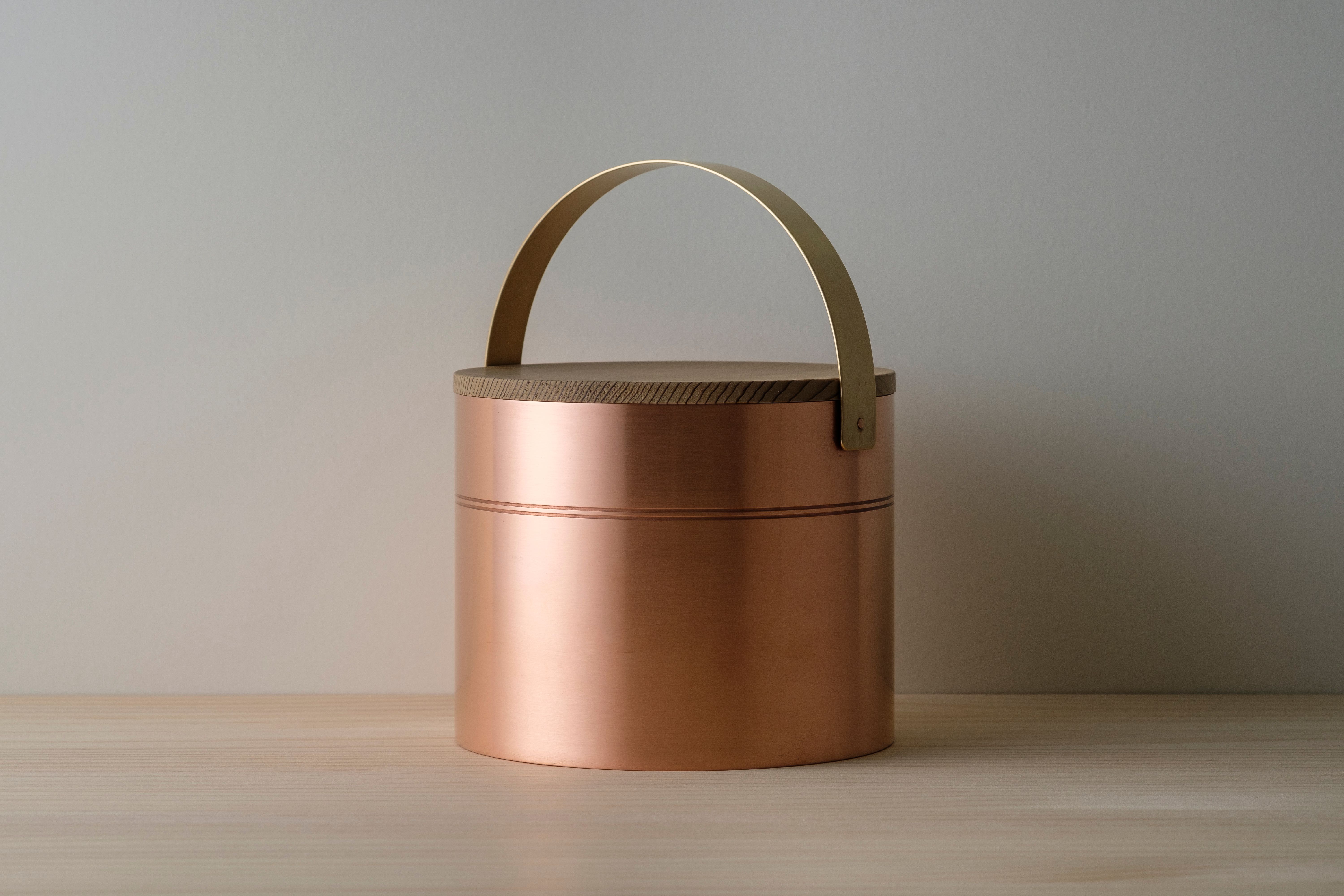 Icebucket in copper, brass and jindai-sugi wood on wooden table top