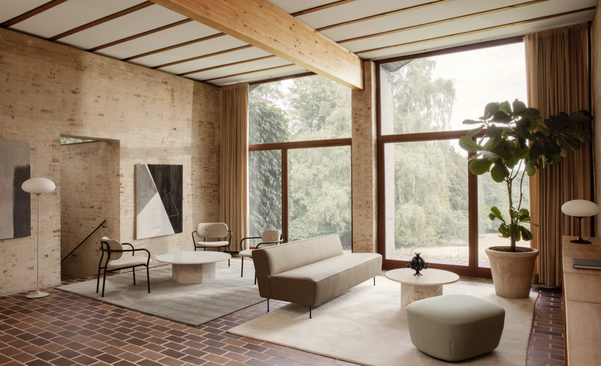 Large high-ceiling living room with soft upholstered furniture, large rugs and brick floor