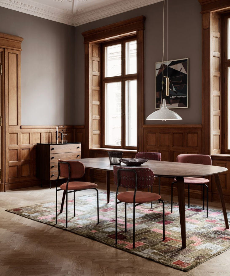 Red upholstery chairs with metal frame around a wooden dark dining table in a classical apartment