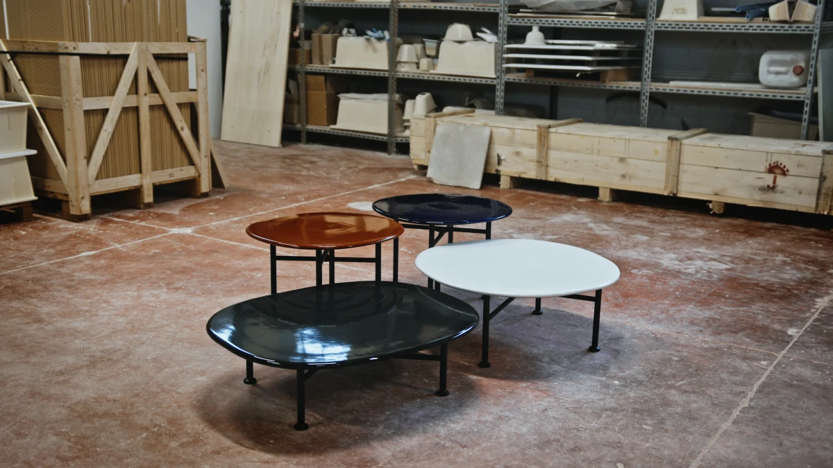 Four tables with black legs and ceramic glossy tops in a warehouse facility
