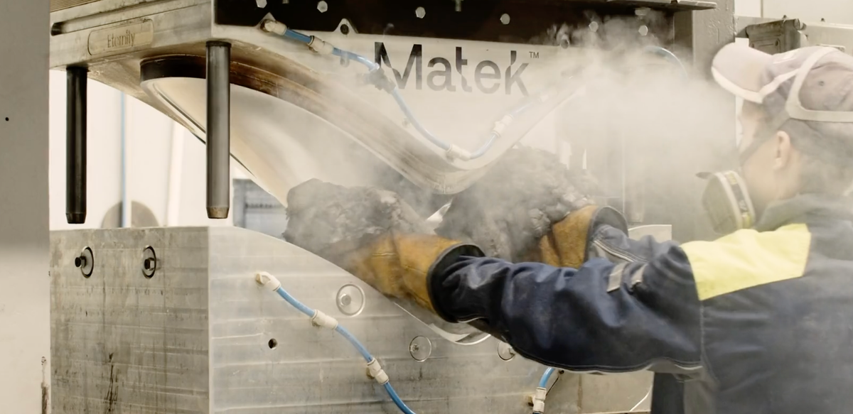 A man in front of a press moulding machine