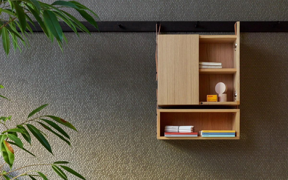 Wooden cabinet hanging on black rack on tiled wall