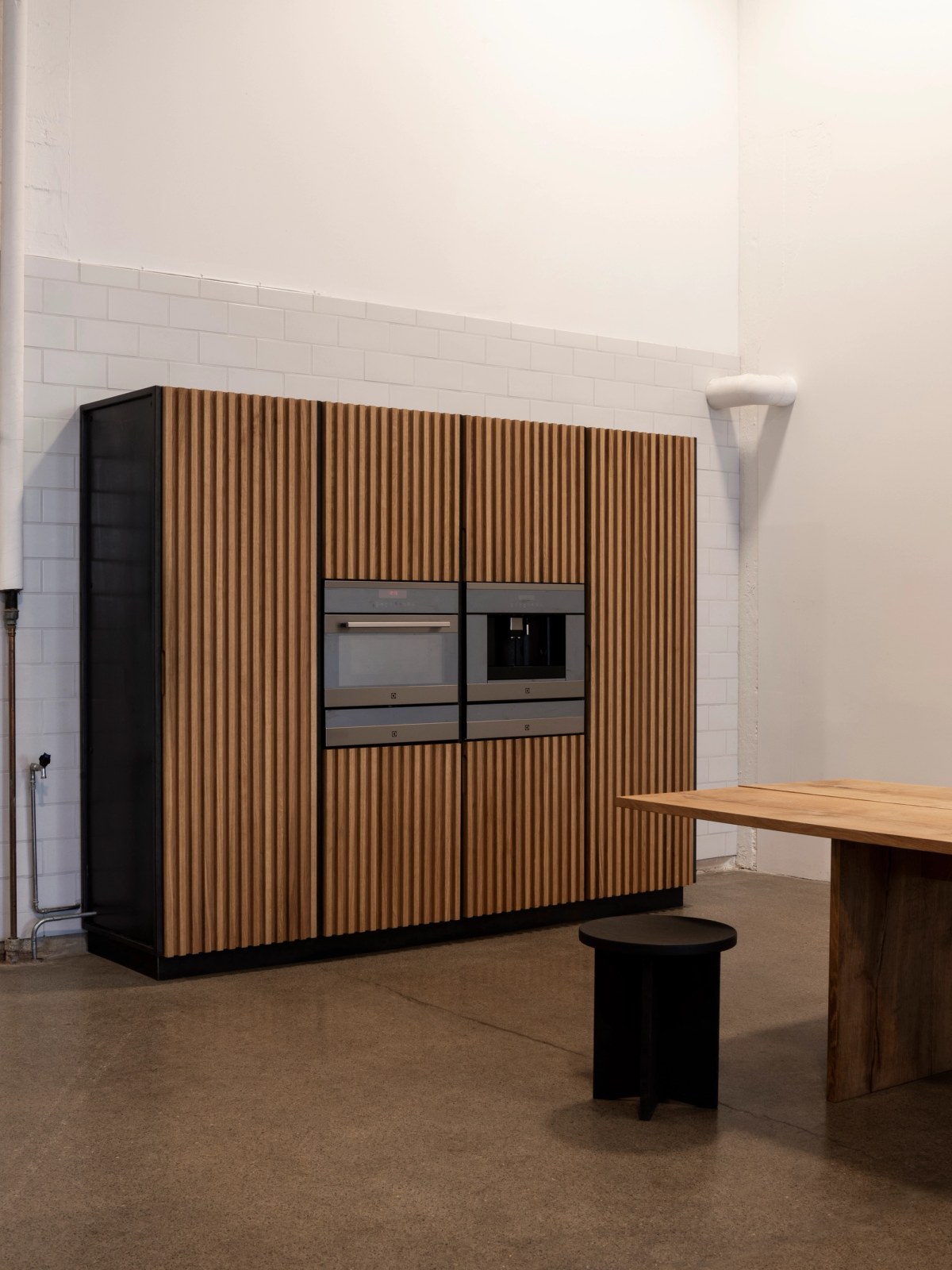 High kitchen cabinet in oiled oak with black steel sides and integrated appliances