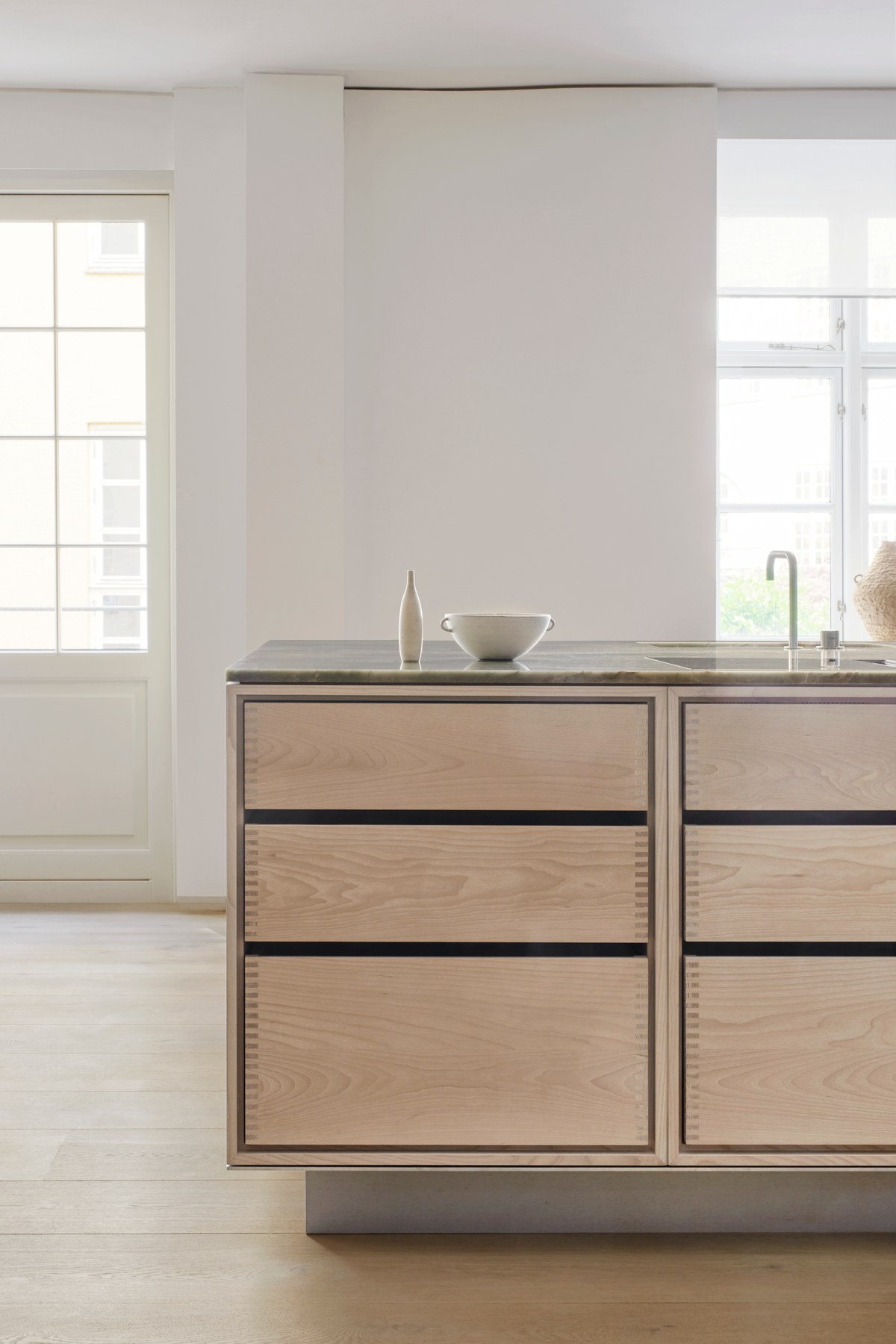 Kitchen island in light ash with stone top and decorative objects