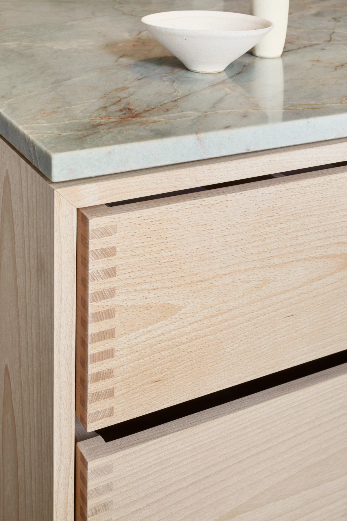Kitchen island with stone top and drawers in light ash wood