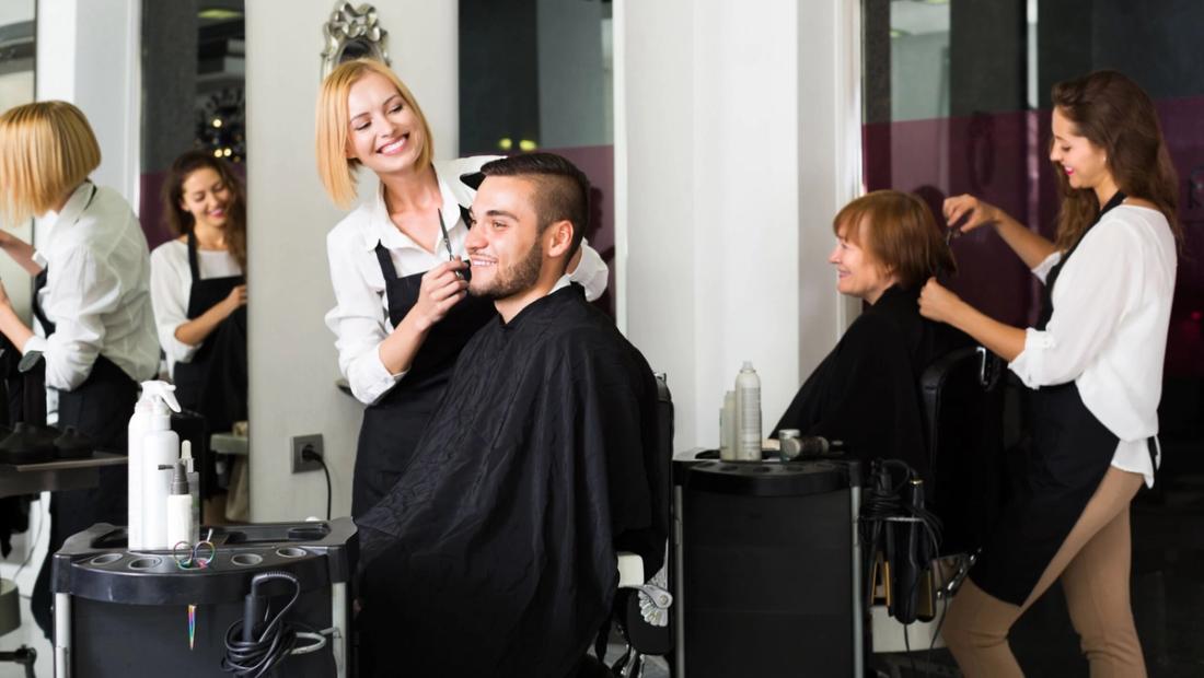 Smiling stylist finishing a client's hairstyle