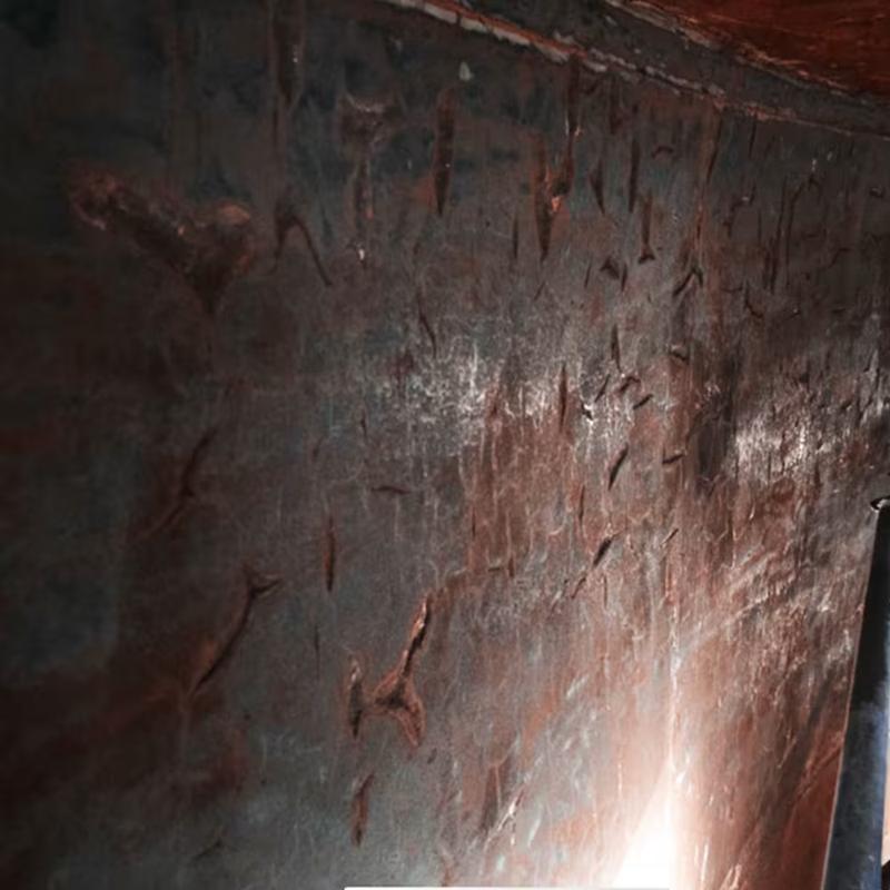 Close-up of cracking and pitting on the inside of a steel wall