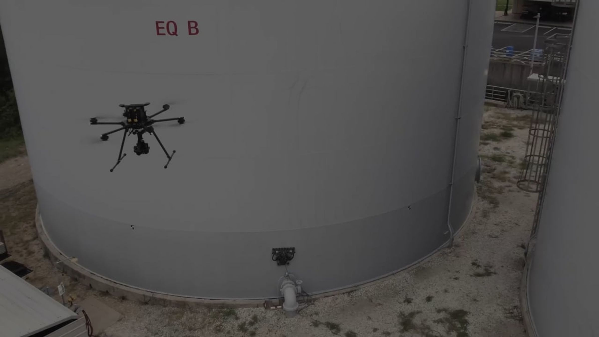 Drone and crawler robot inspecting a white storage tank