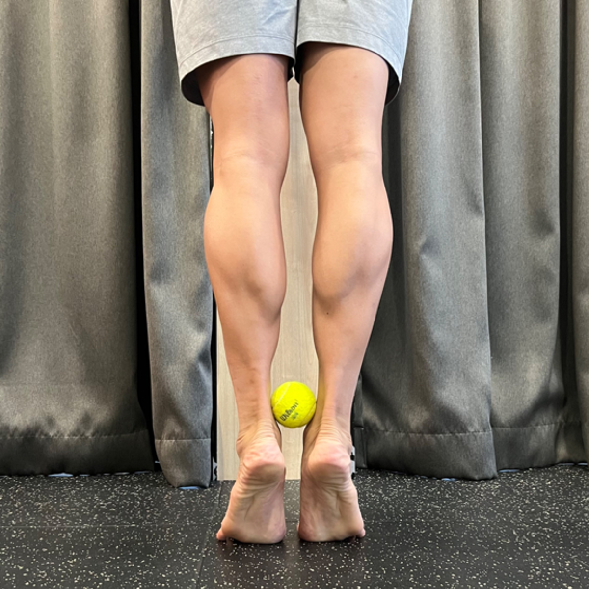 Heel raises with a tennis ball held between the heels.