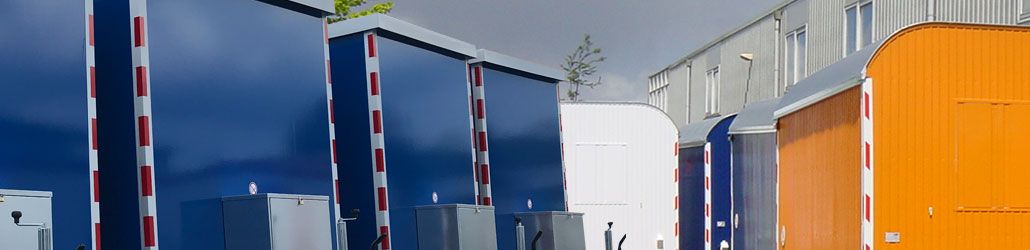 Rij schaftwagens met platte en ronde daken in verschillende kleuren, opgesteld buiten bij een bedrijfspand.