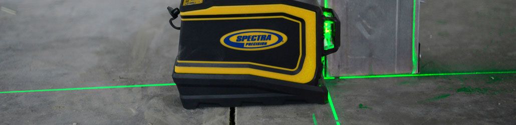 Spectra kruislijnlaser projecteert groene lijnen op betonnen vloer en wand voor nauwkeurige uitlijning.