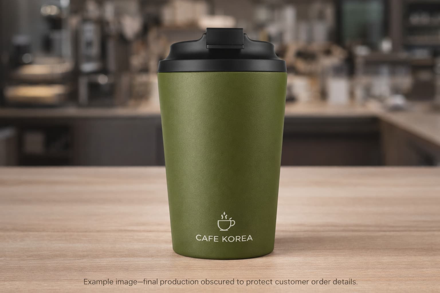 Olive green matte insulated tumbler with laser style cafe logo in a coffee shop setting concept image for custom member gift project