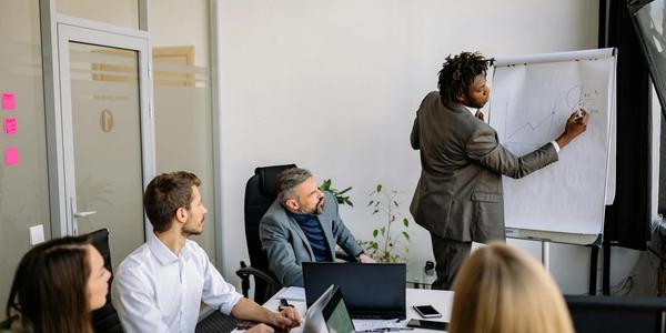 A diverse team in a modern office engaged in a strategic business meeting led by a presenter.