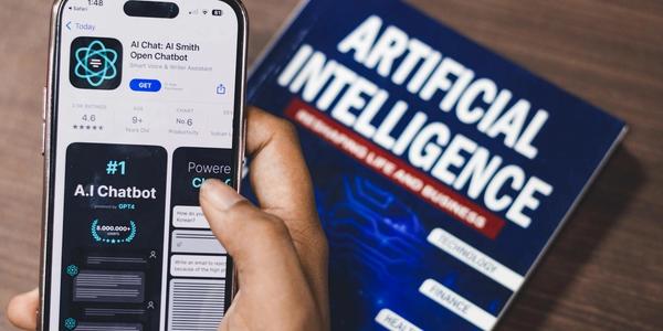 Smartphone displaying AI app with book on AI technology in background.