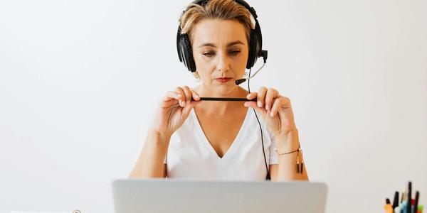 Adult woman in headphones using laptop for remote work in a home office setting.