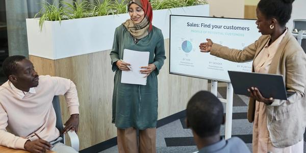 Team of professionals discussing sales strategy during a business presentation in a modern office.