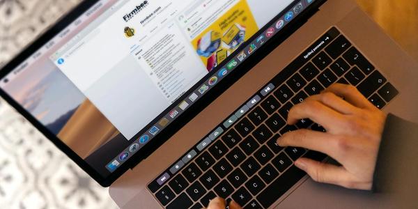 Hands typing on a laptop at a desk, engaging in online work, and navigating social media.