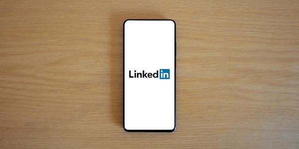 Top view of a smartphone displaying the LinkedIn logo on a wooden surface.