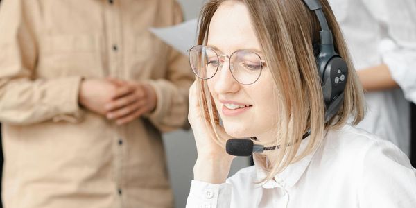 Professional woman providing customer support with a headset in an office setting.