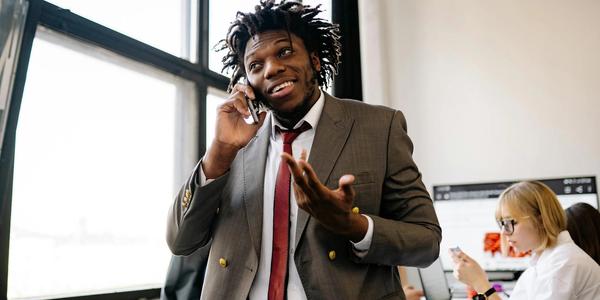 Professional businessman smiling while talking on the phone in an office setting.