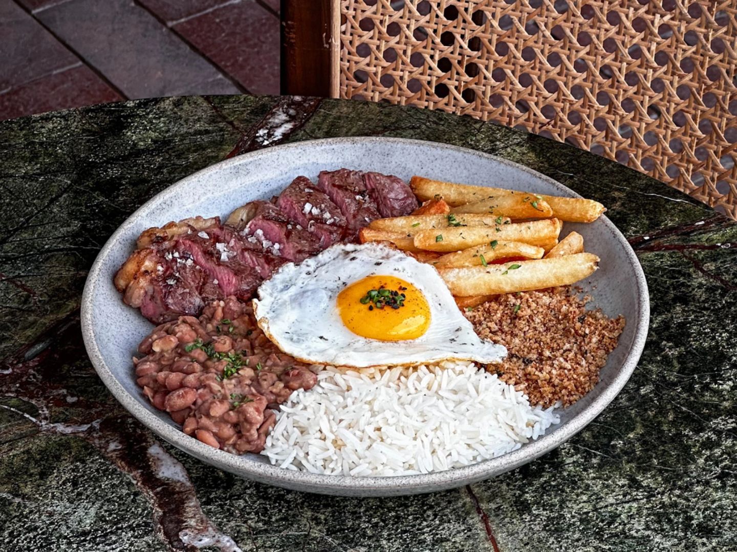 Sliced steak with rice, beans, fries, a fried egg, and farofa.