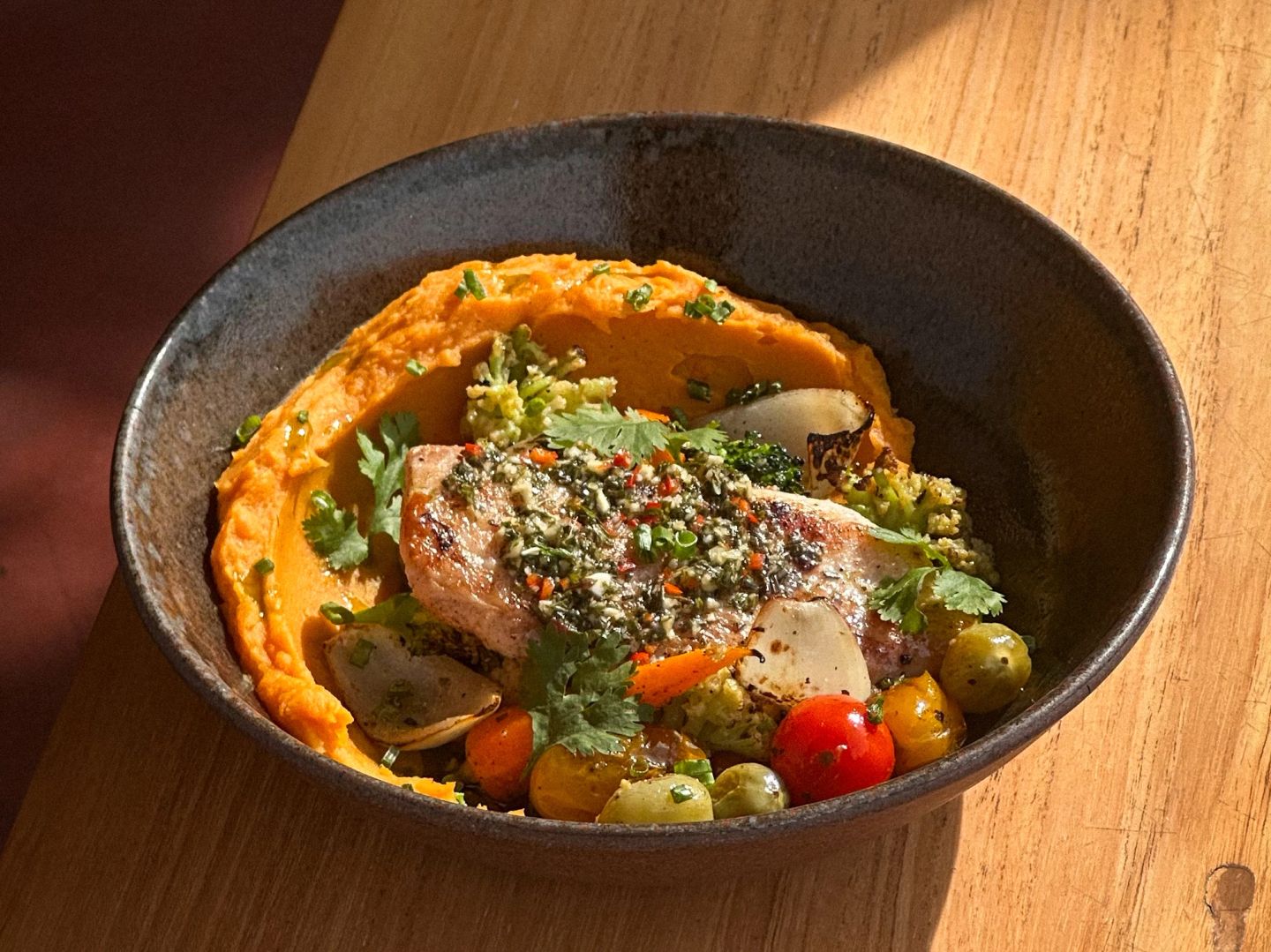 Grilled fish over sweet potato orange purée with herb salsa, roasted vegetables, and cherry tomatoes.