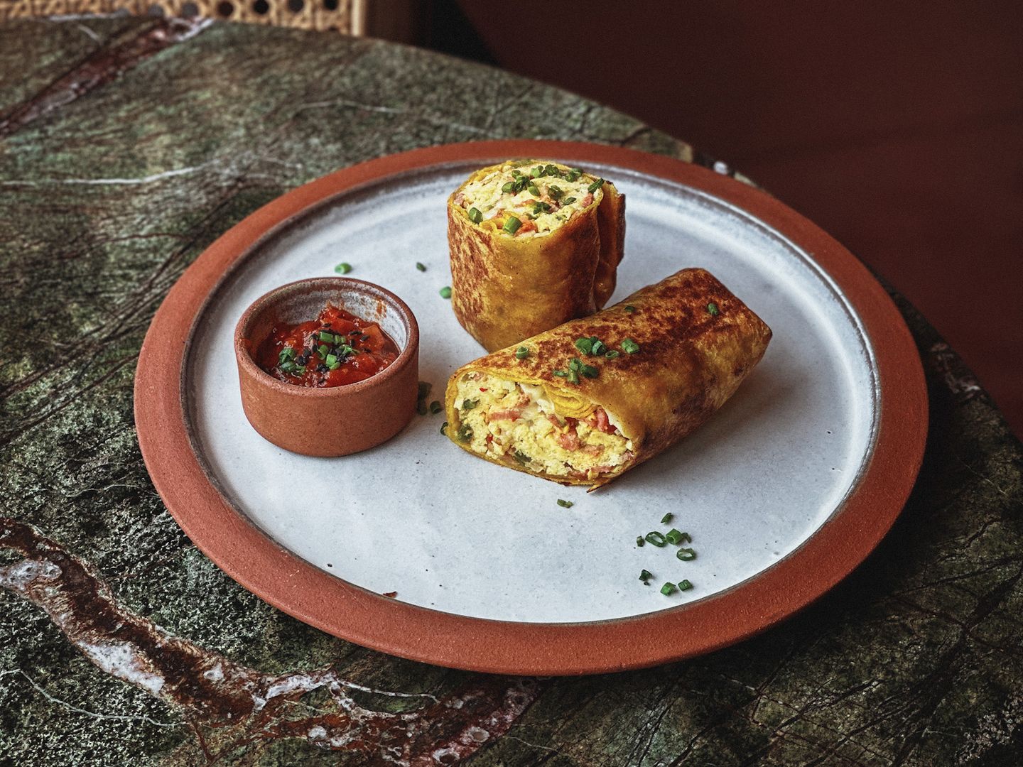  Golden egg wrap with melted cheese, sliced and served with a side of chilli relish.