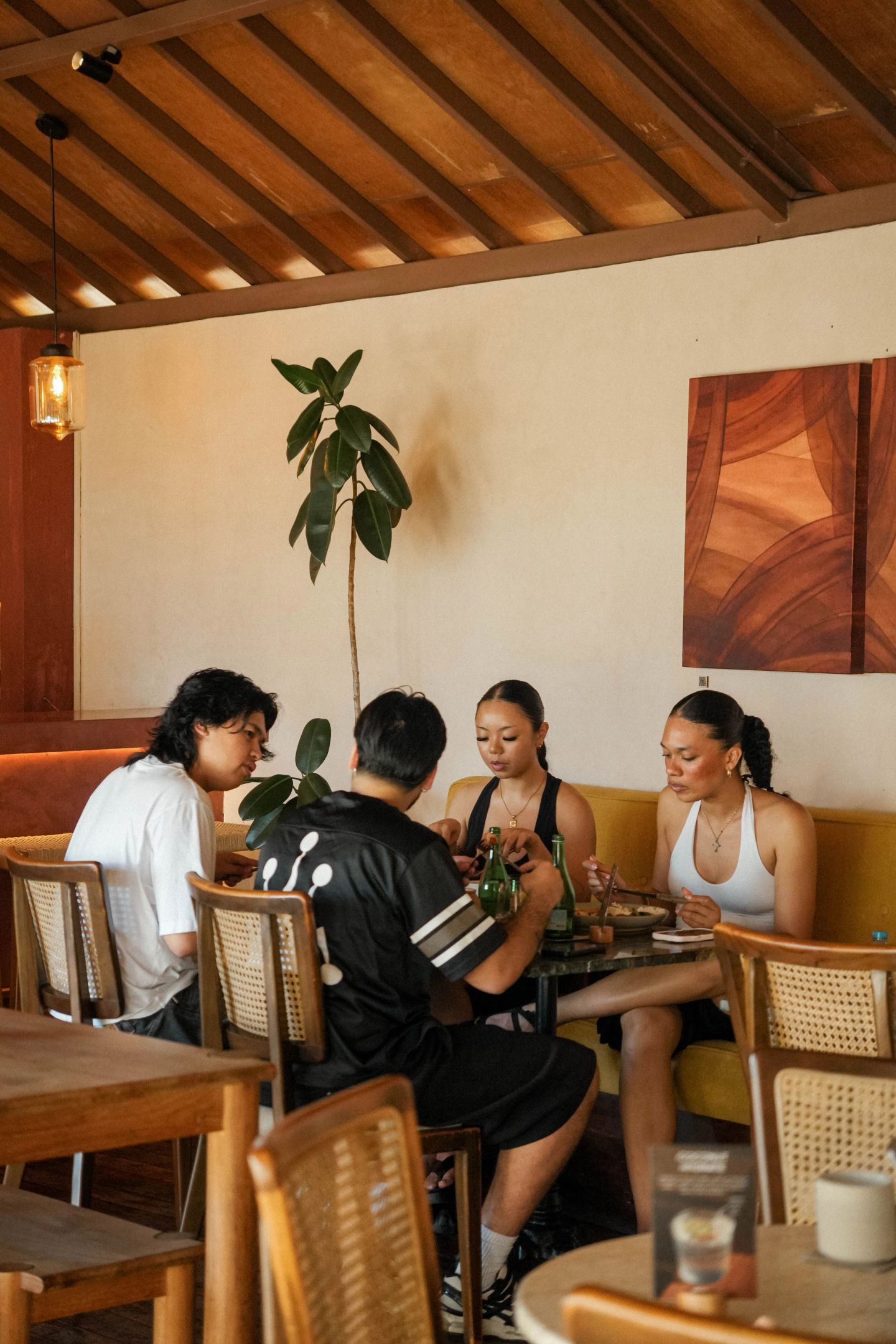 Friends eating lunch at House of Sunday, warm wood ceiling and dining room, Canggu