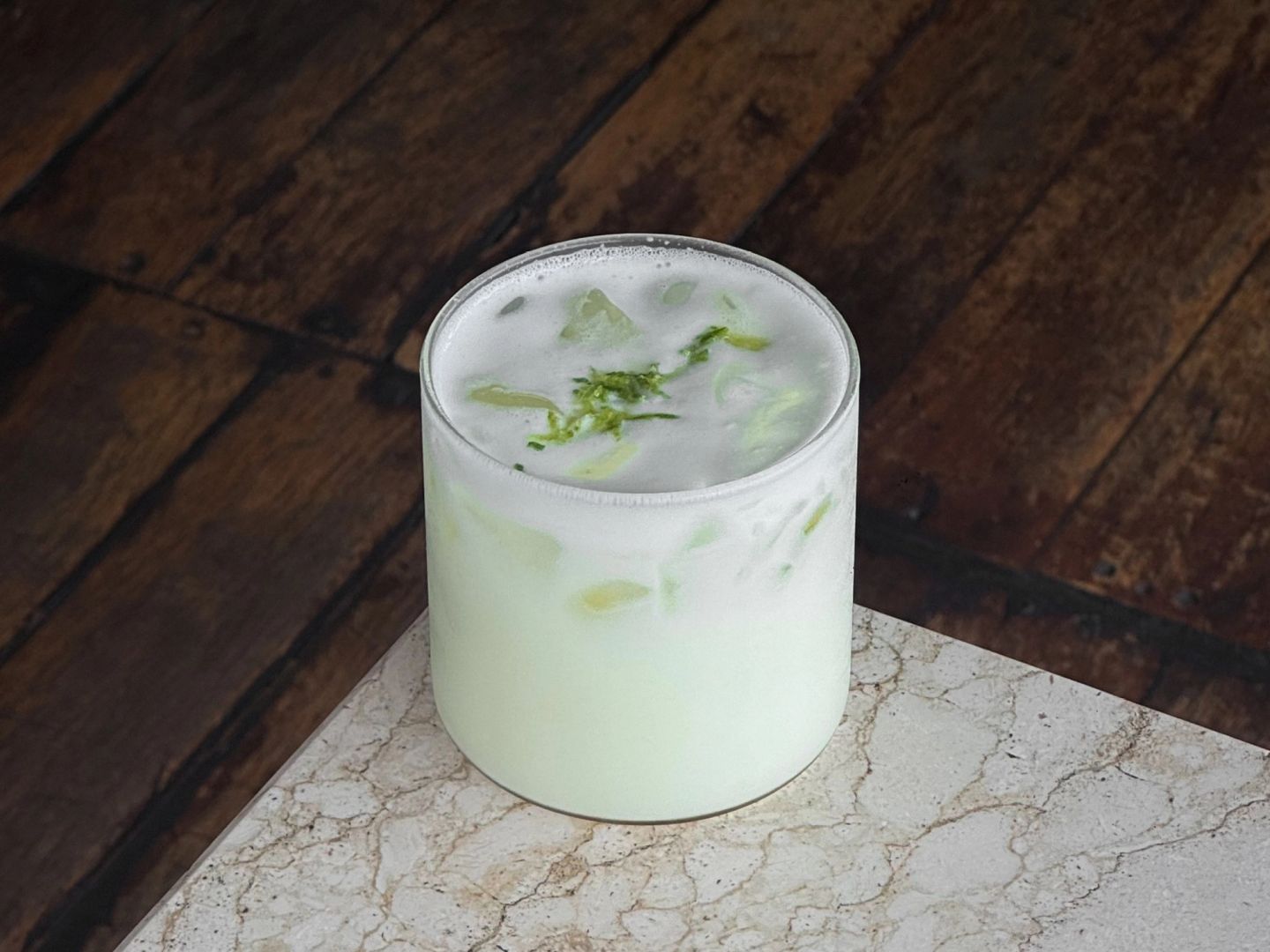 Cloudy pale-green limeade with condensed milk over ice, topped with lime zest.