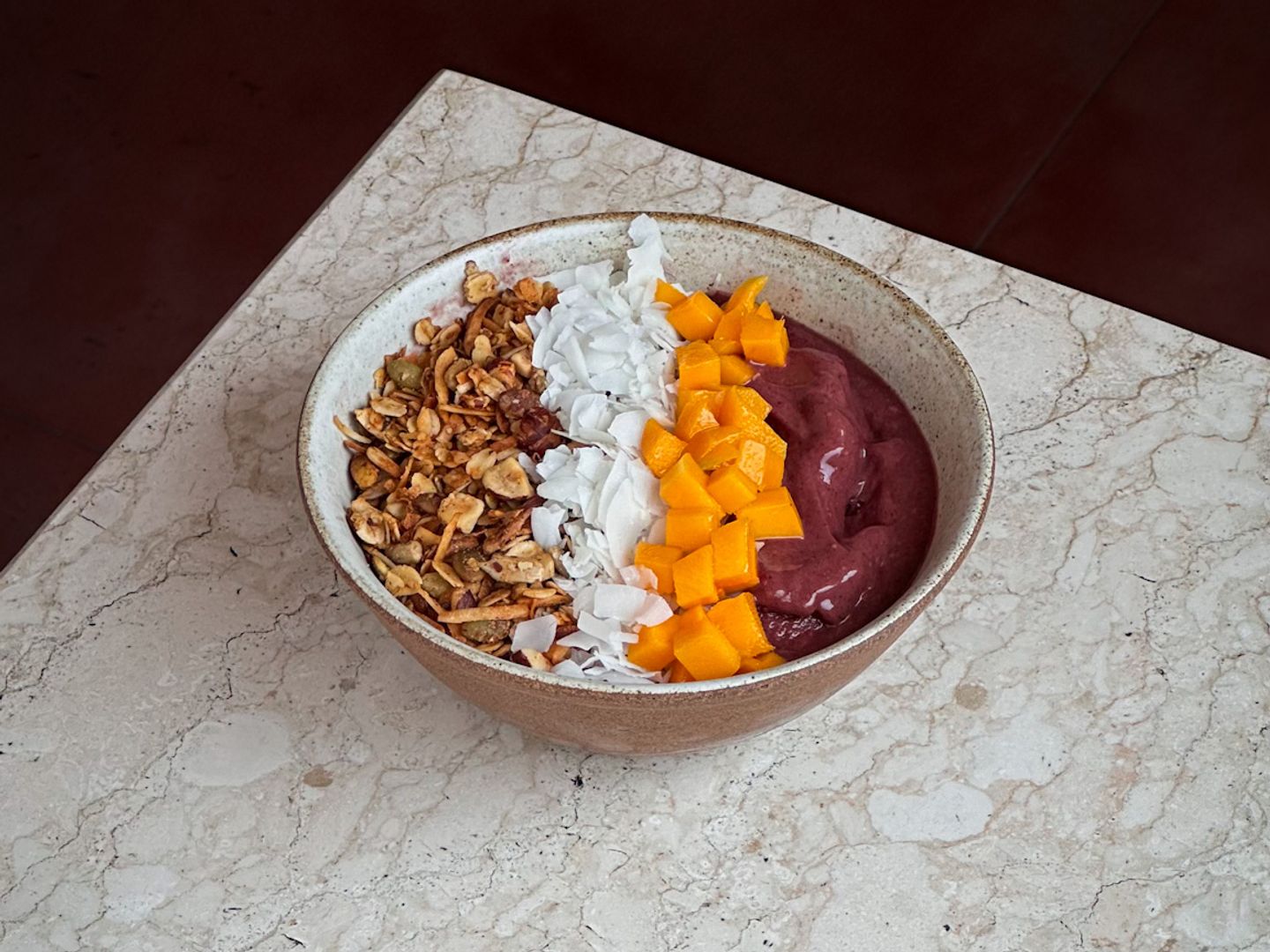 Açai blend topped with granola, coconut flakes, and fresh mango cubes.
