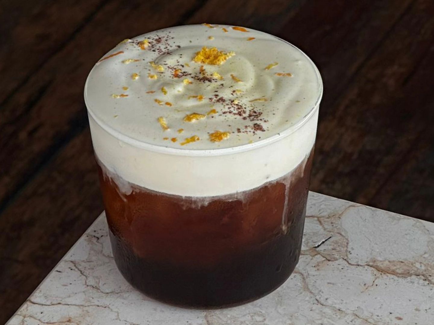 Iced cold drip coffee topped with honey foam, citrus zest, and a dusting of nutmeg.