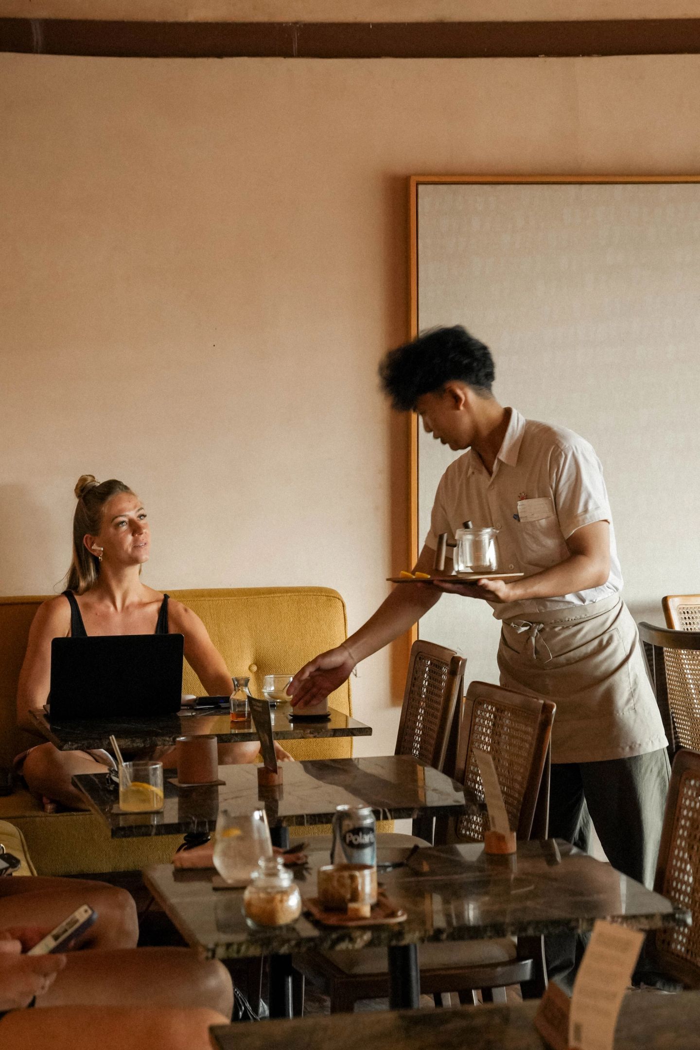 Server bringing a drink to a table at House of Sunday, warm dining room, Canggu
