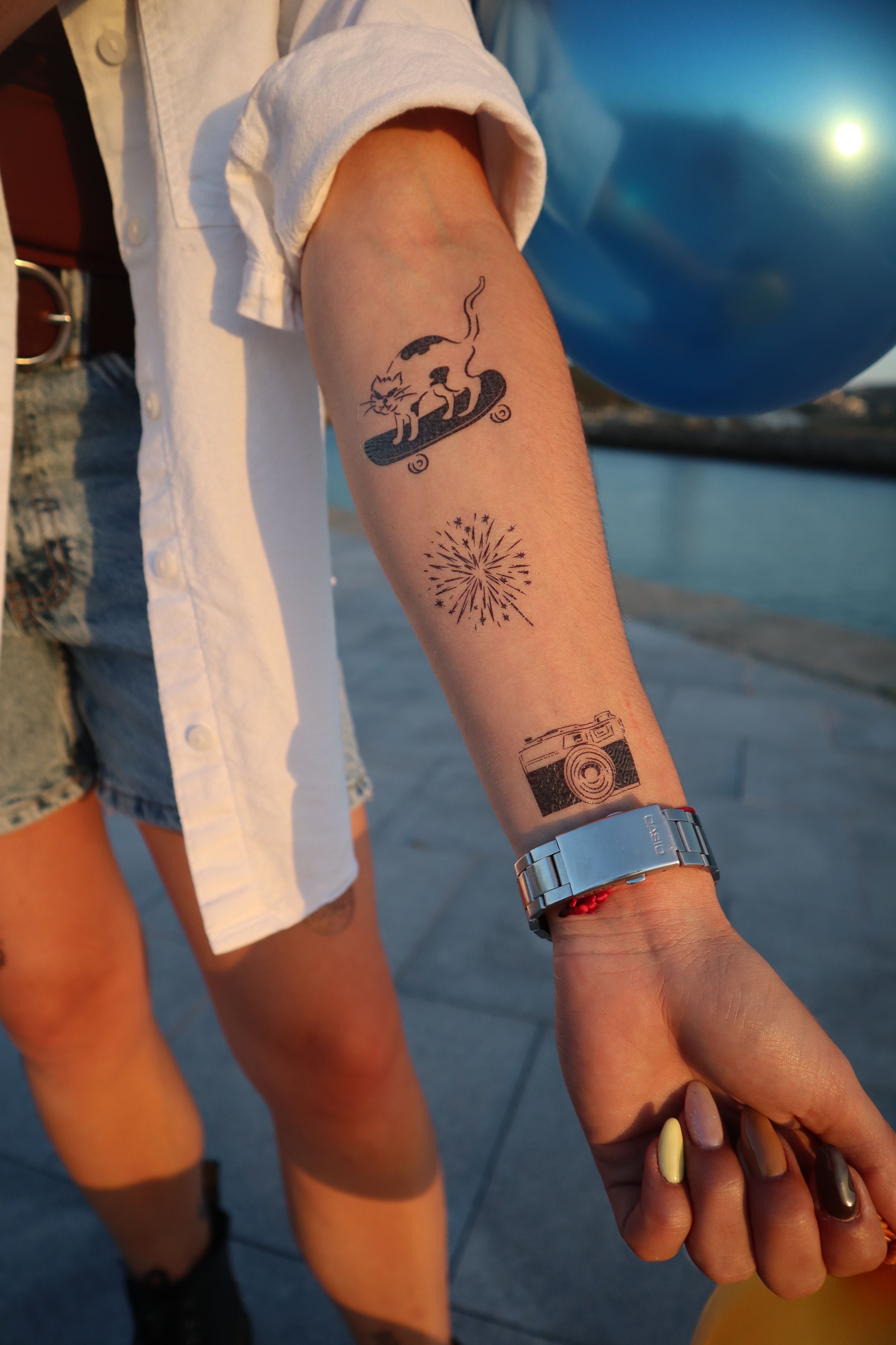 temporary tattoos on forearm, a camera a funny cat skating and fireworks