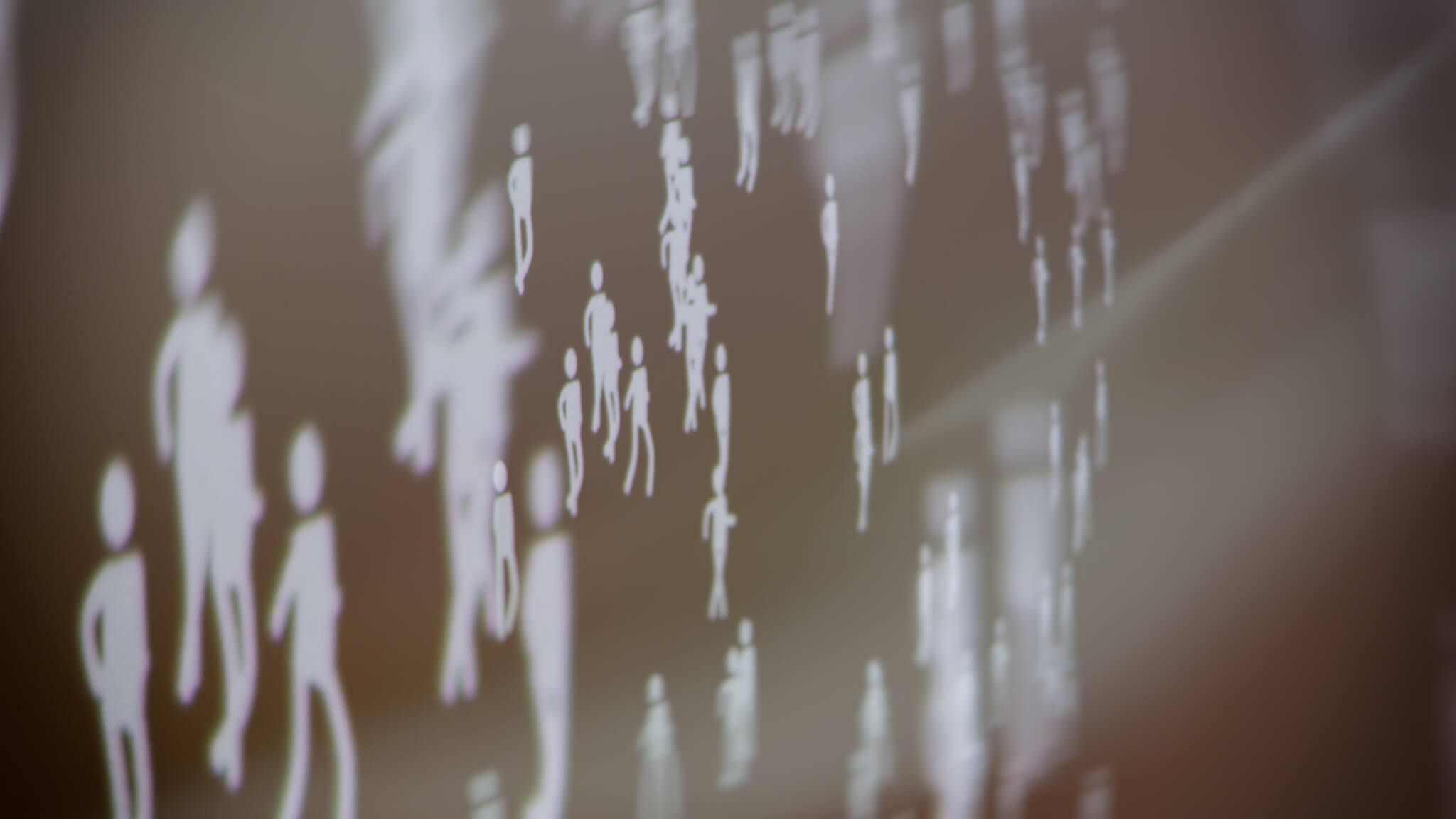 An abstract photograph of hundreds of stick figures walking around at different speeds and sizes.
