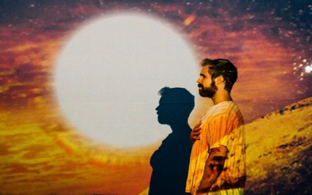 A photograph from a interactive theatrical performance. A bright sun halo follows the actor and acts as spotlight.