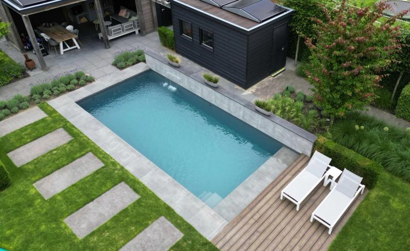 Een strak zwembad met waterelement en verhoogde muur