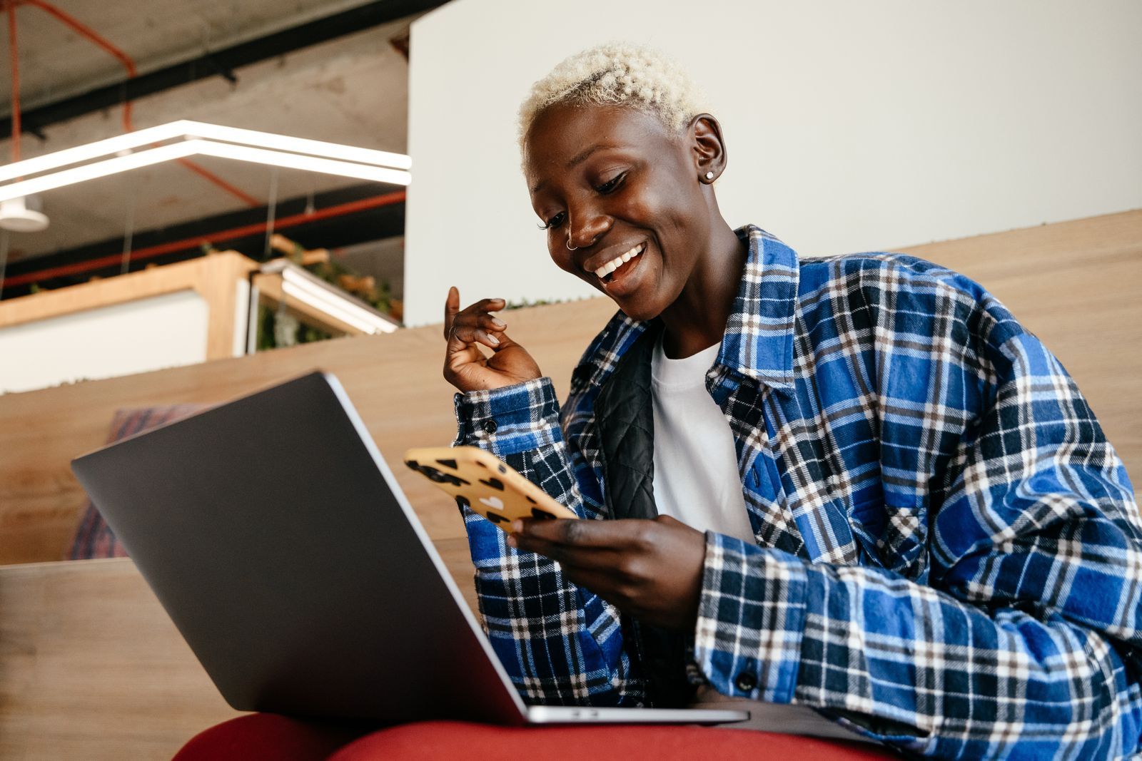 Smiling South African business owner checking her phone while working on a laptop