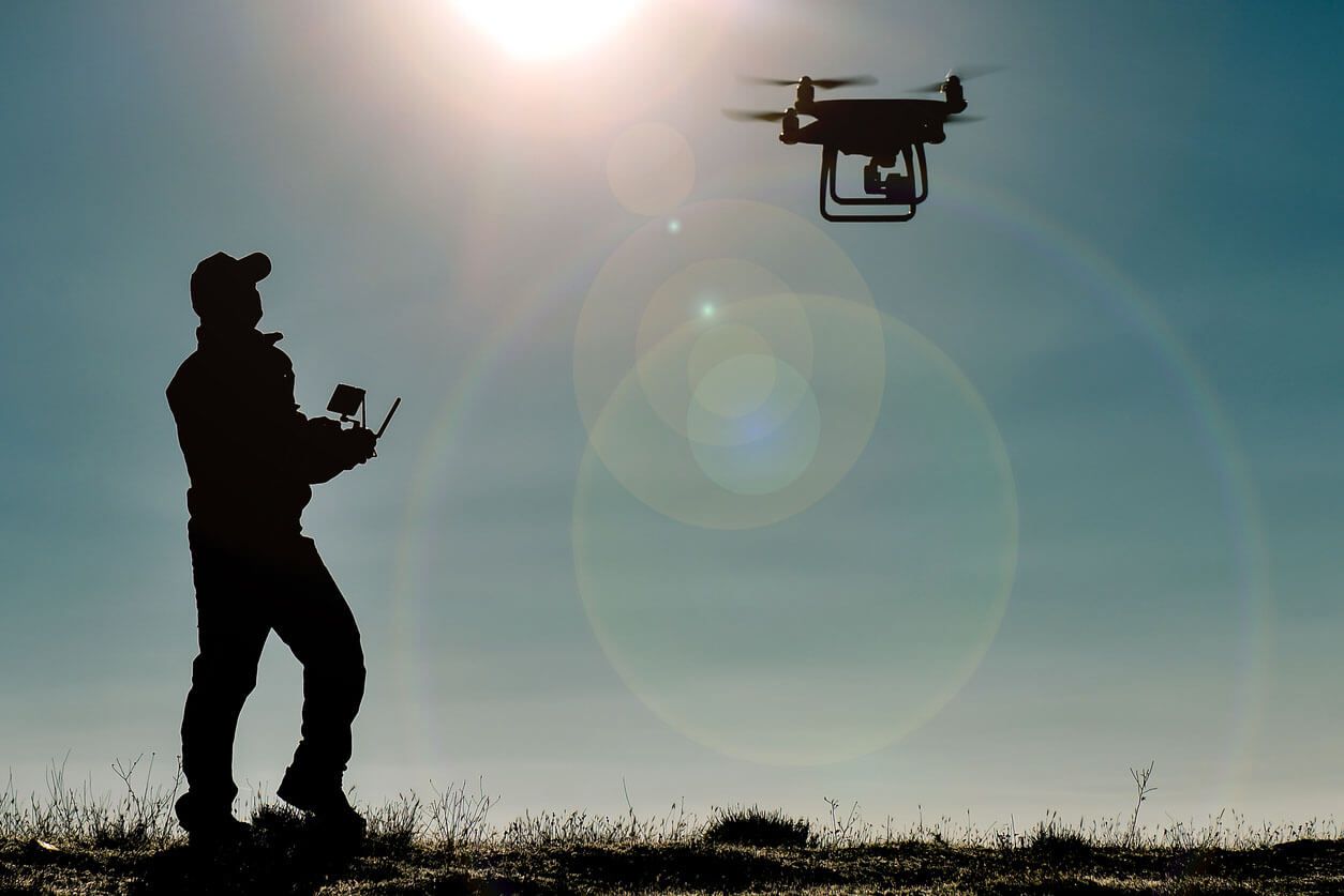Silhouette of a person flying a drone