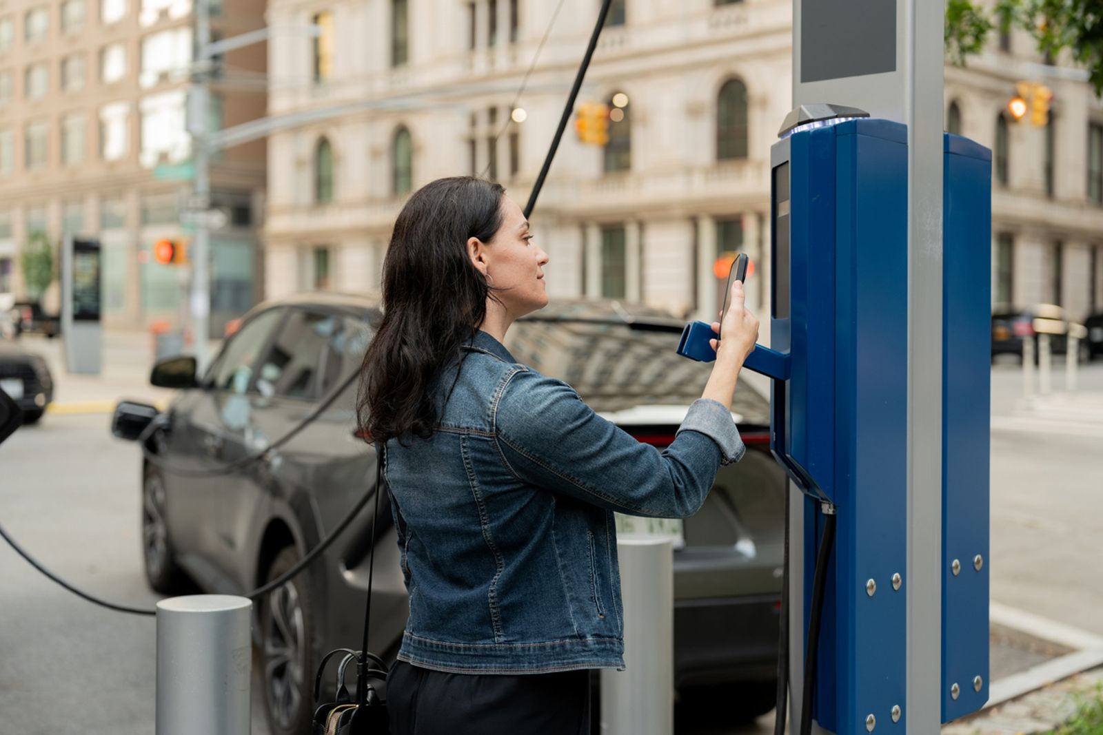 mujer pagando por carga de vehículo eléctrico
