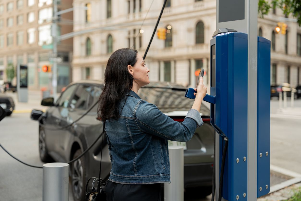 mujer pagando por carga de vehículo eléctrico