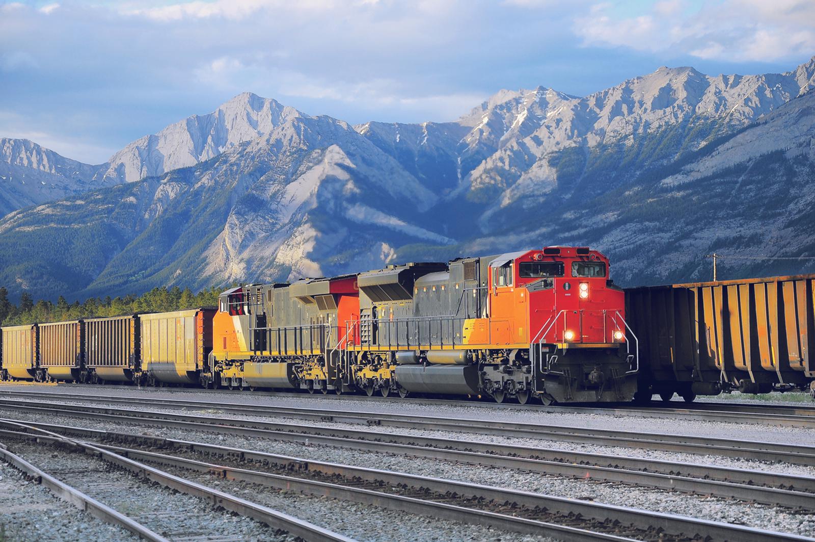 Freight container train in the forefront with a mountain range in the background.