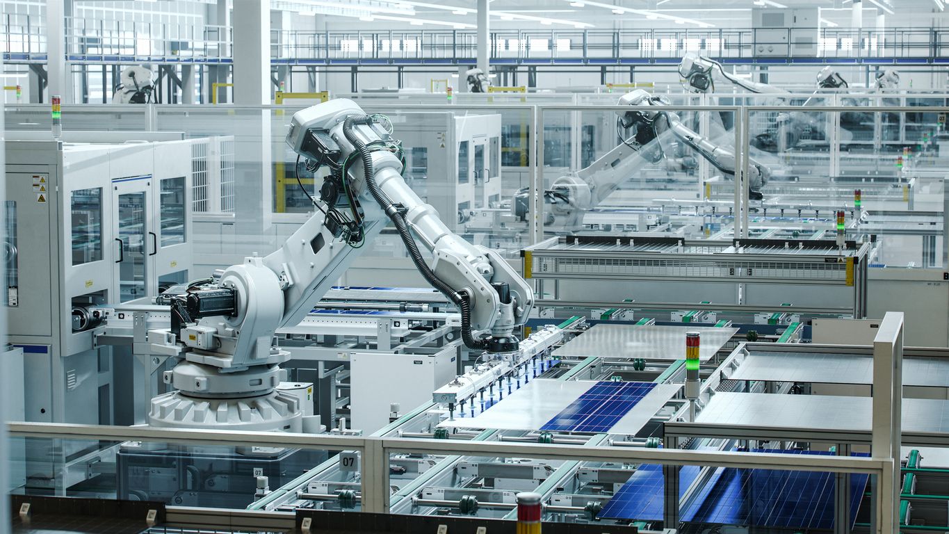 Solar Panels are being assembled on conveyor with a white industrial robot arm