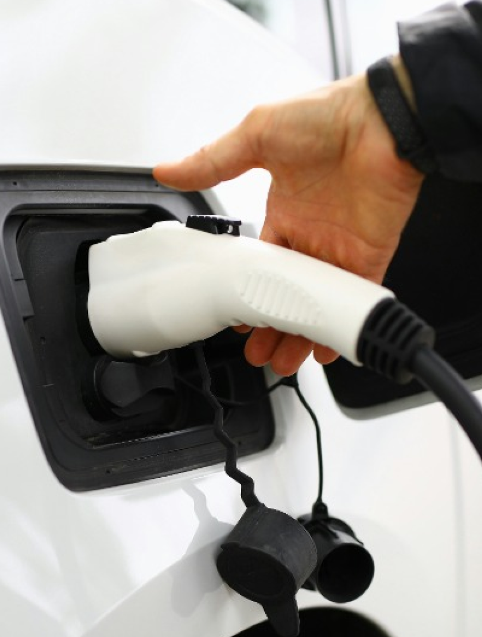 An electric vehicle user plugs in their car to a charger