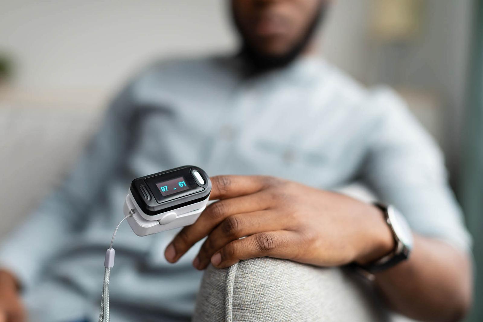 man sitting on a couch with a pulse monitor on his finger