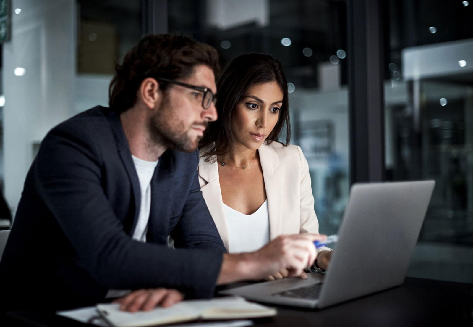 Coworkers collaborate in front of a laptop computer