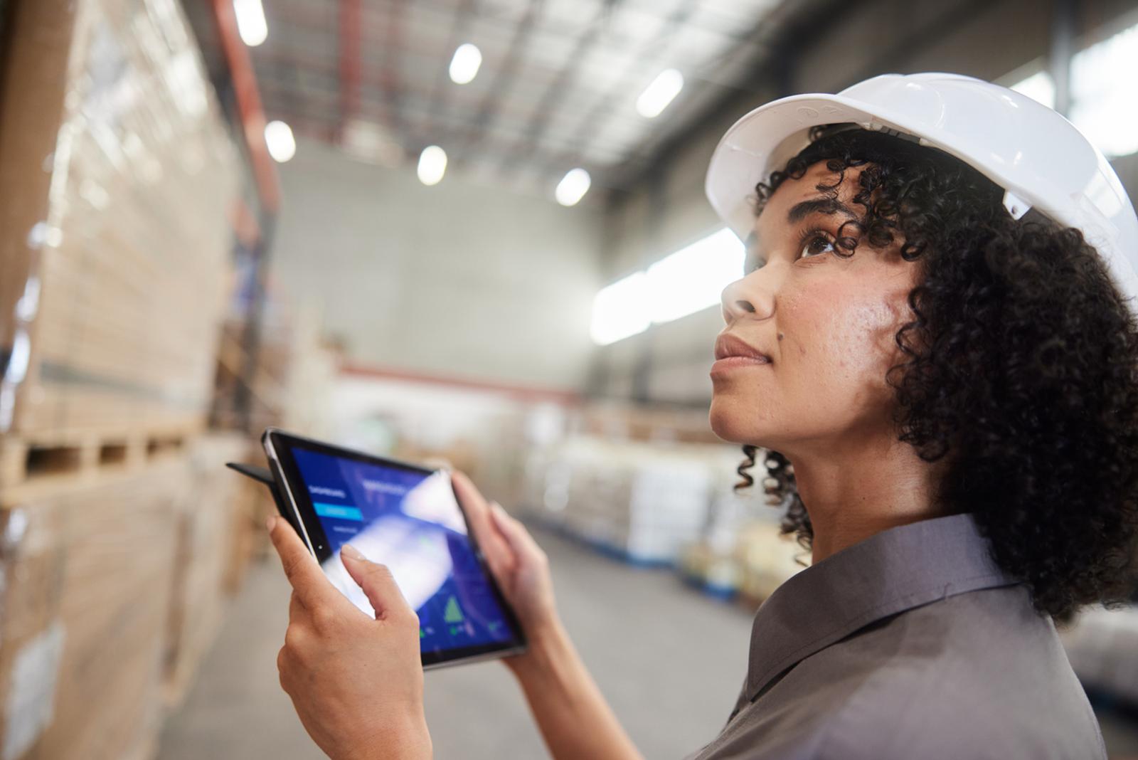 Female warehouse employee monitoring inventory with a tablet