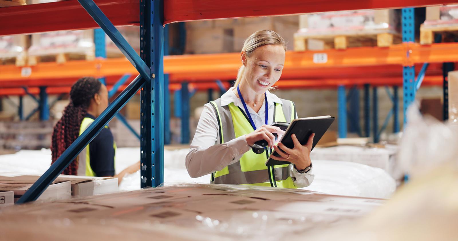 Woman with a low ponytail using a scanner and tablet to track inventory in warehouse