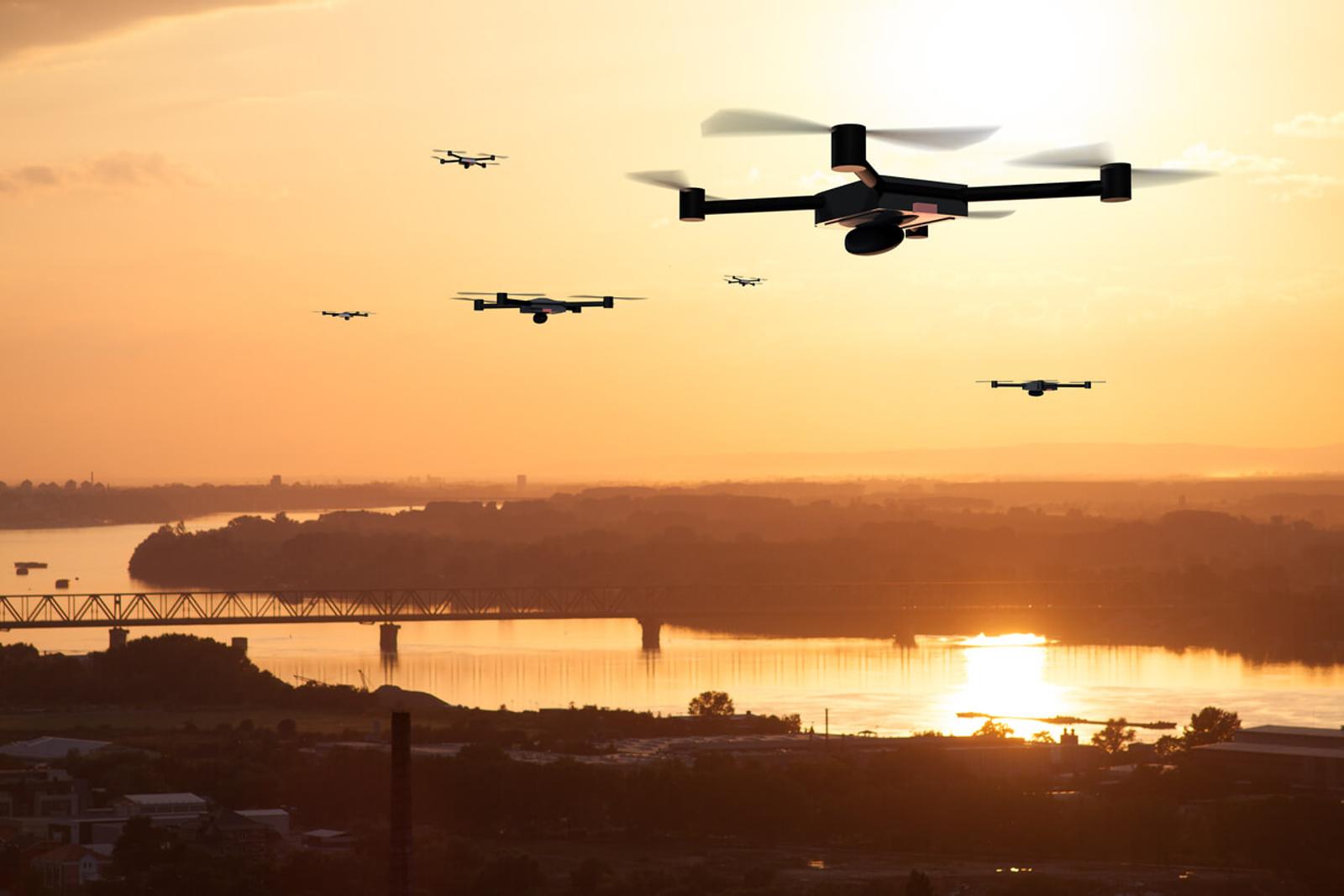 Drones flying above water at sunset