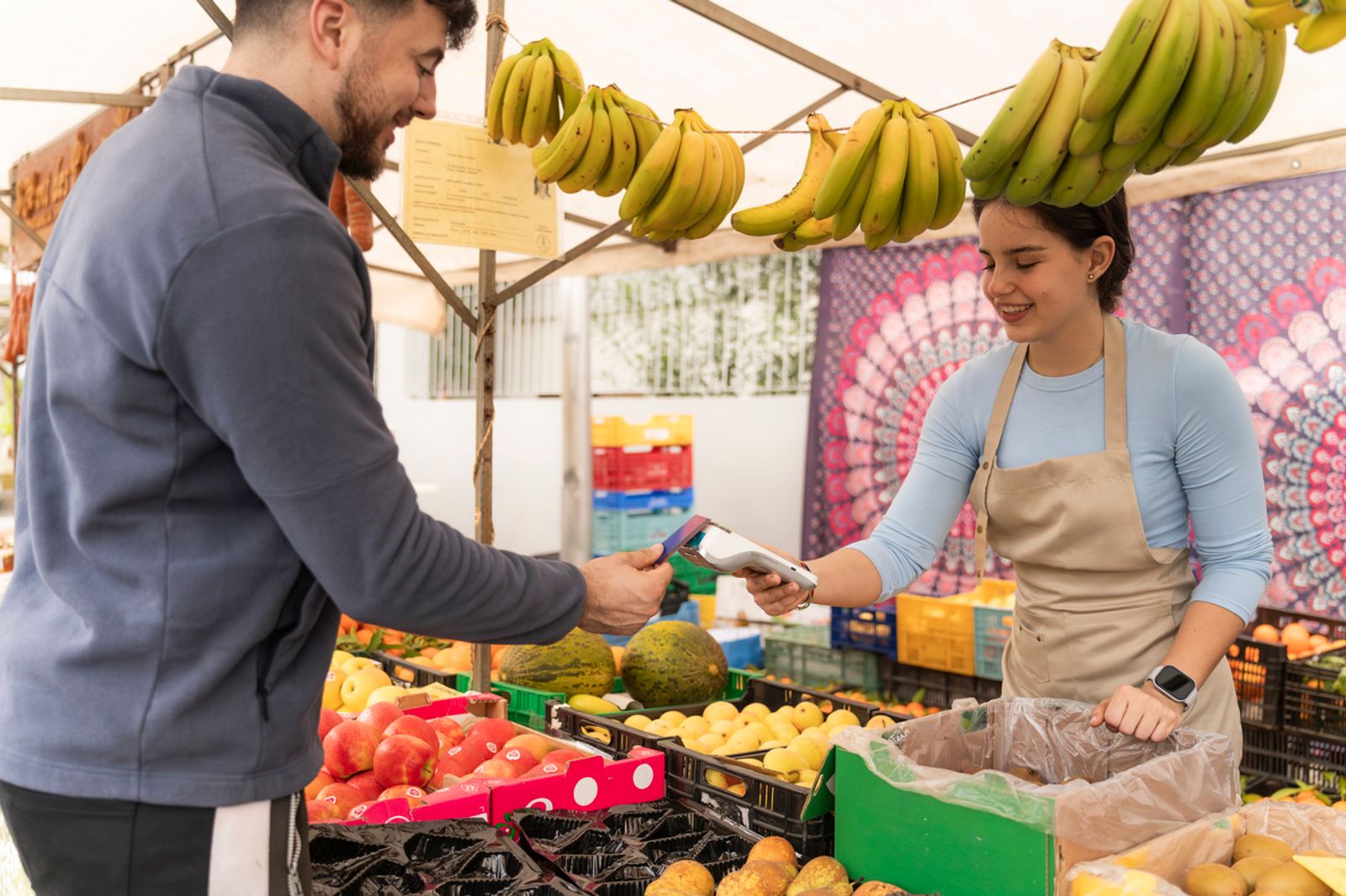 vendor processing a contactless payment at outdoor fruit stand