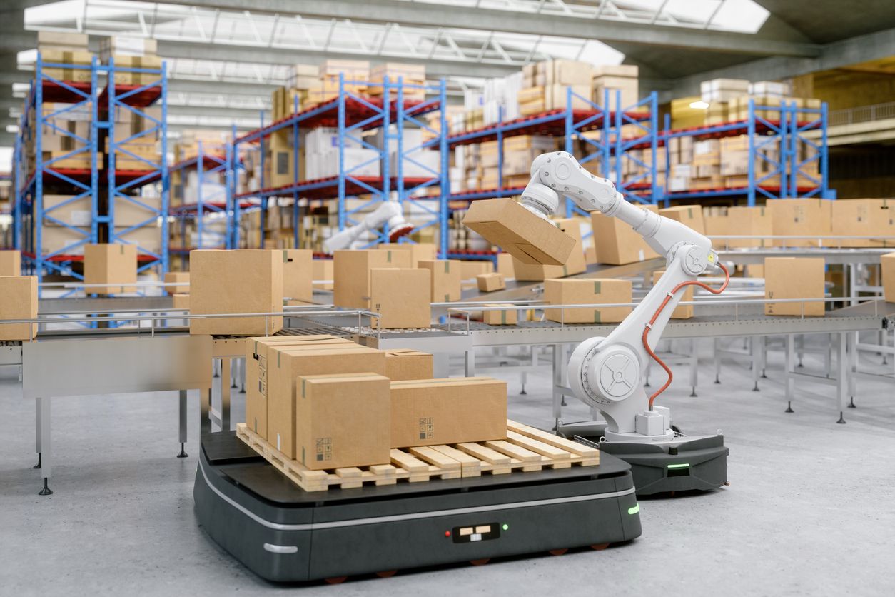 A robotic arm packs boxes on an assembly line